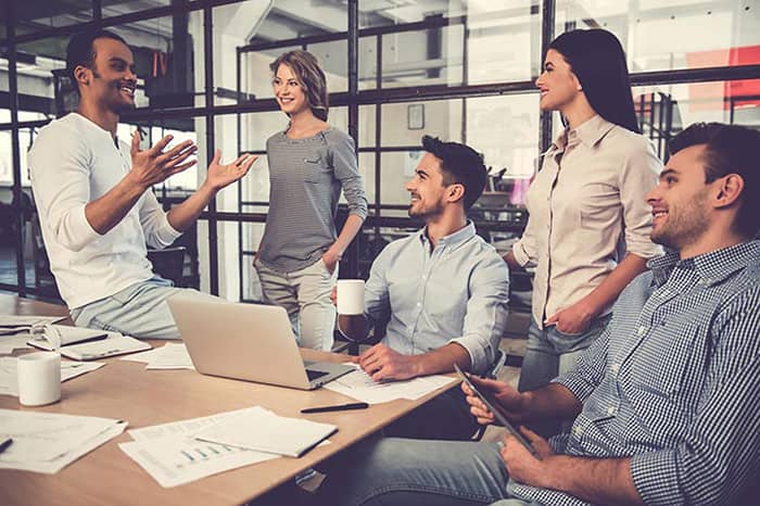 A group of coworkers in a conference room speaking together